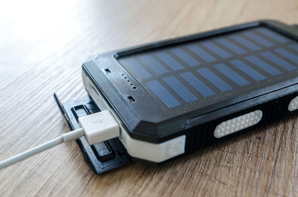 Close-up of a rugged solar power bank charging a device, showcasing efficient power solutions for devices while camping and off-grid adventures.